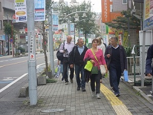 私服姿のドイツ人4名以上が、歩道を歩いている様子を、正面から撮影した写真