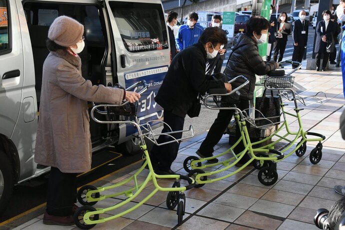 乗り合いバスから降りた三人の高齢女性が、それぞれ薄緑色のカートを押して歩きだそうとしている写真
