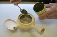ティースプーンで茶缶から茶葉を急須に入れている写真