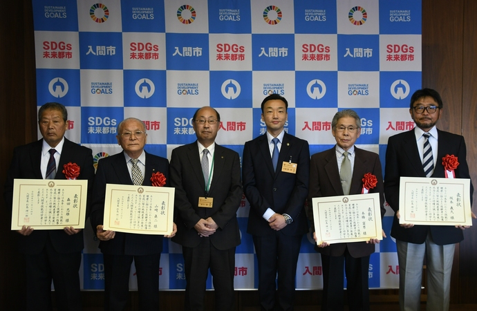 2人の男性と表彰状を持った4人の男性の写真