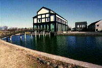 池の脇に建つ白い壁と黒い梁が見える東野高校の外観の写真