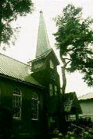 空に向かい伸びるような三角すいの尖った屋根が特徴的な武蔵豊岡教会外観の写真