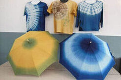 おしゃれで特徴的な模様でカラフルなカラーをした3枚のTシャツと2つの広げられた傘の写真