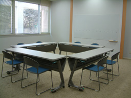 長机4つを四角く並べて椅子を2脚ずつ配置した会議室の写真