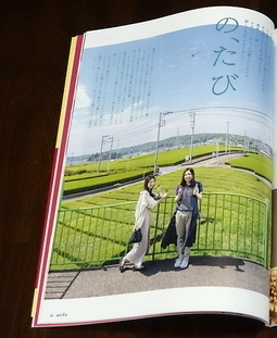 「の、たび」と書かれた田んぼのそばにある柵に寄りかかっている2人の女性の写真のページを開いて机に置いている写真