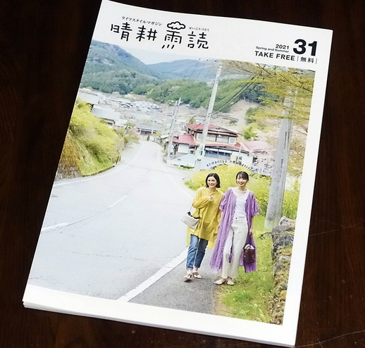 道路脇の歩道を歩いている2人の女性が表紙になっている冊子が机に置かれている写真