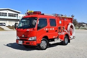 体育館前で停車する赤い消防ポンプ自動車を撮った写真