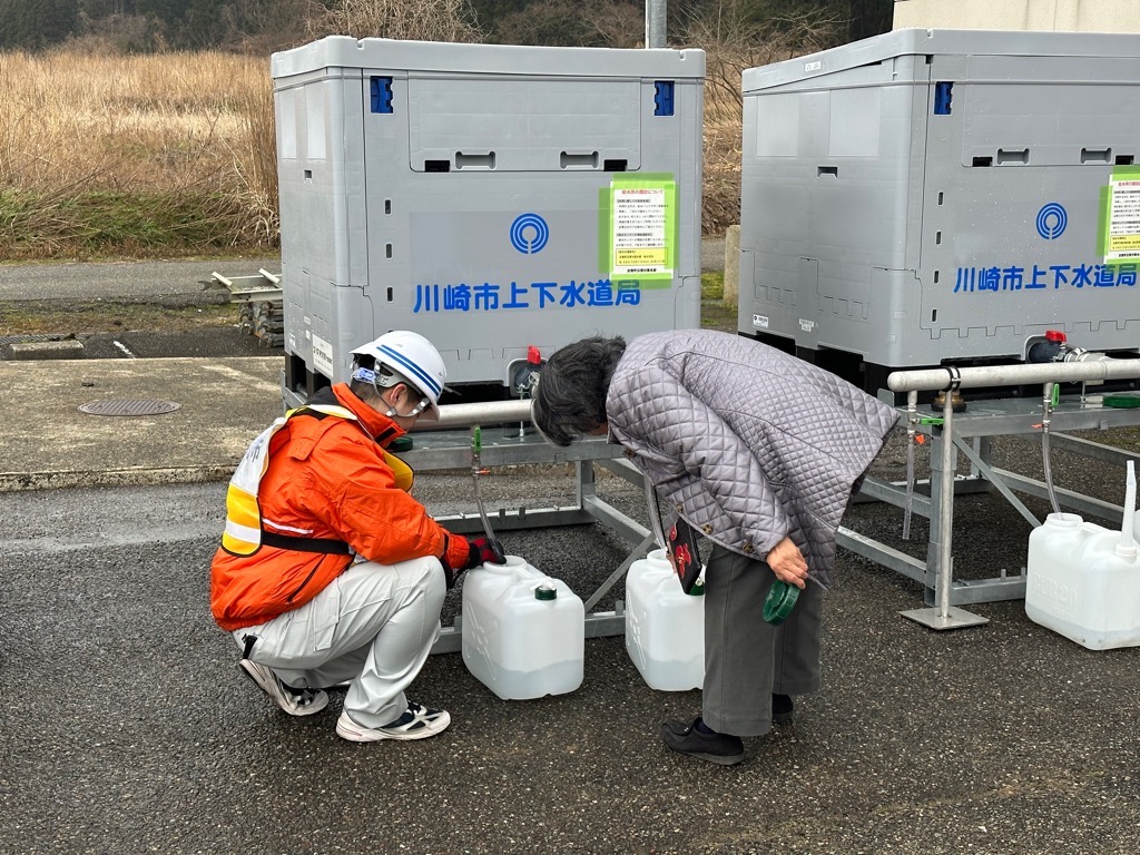 志賀町稗造スポーツセンターにて仮設タンクからポリタンクへの給水を手伝う様子