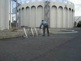 円柱状の建物の前に給水栓を設置する作業員の写真