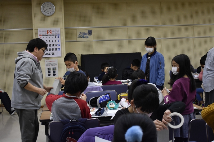 子どもたちが女性と話したりテーブルで何かを作っている写真