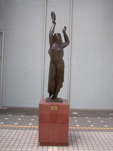 頭上にタンバリンを掲げて演奏している女性の銅像の写真