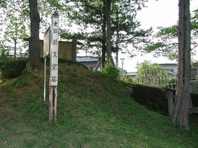 木々と芝生が生えた緩やかな坂の中の「史跡新久窯跡」と書かれた木の柱の写真