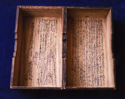 内側に文字がびっしりと書かれた二つの木箱の写真