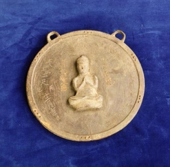 文字と仏様が掘られた金色の円盤の写真