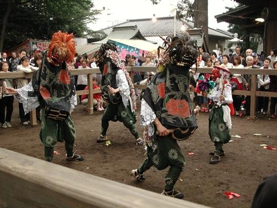 木の柵の中で踊る獅子舞とそれを眺める観客の写真