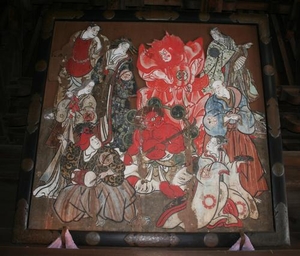 木に描かれた赤で描かれた人物の周辺に立つ複数の人物の日本画の写真