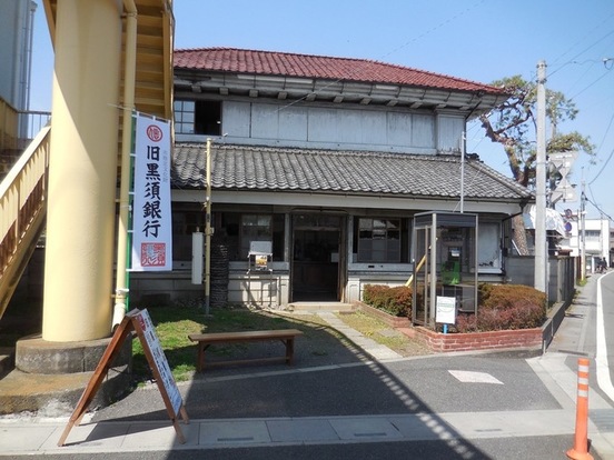 「旧黒須銀行」と書かれたのぼりと二階建て瓦屋根の日本家屋の写真