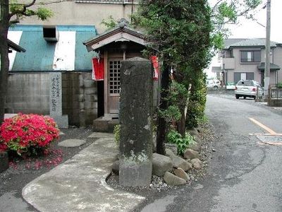 道路わきに立つ祠と石造の写真