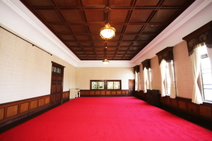 白いカーテンの窓と赤い床の家具のない広い部屋の写真