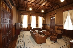 白いカーテンと白を基調とした絨毯と茶色い家具で統一された部屋の写真