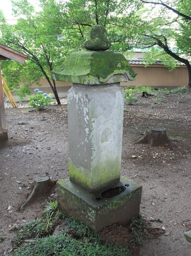 境内の広場に置かれた苔の生えた石塔の写真
