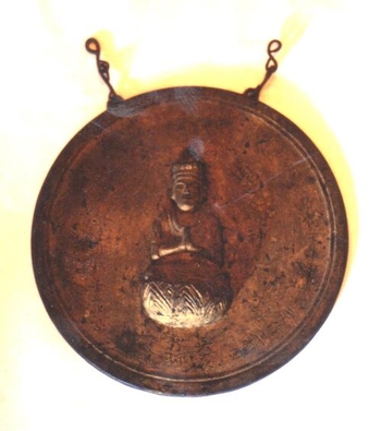仏様の掘られた銅色の円盤の写真