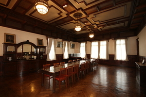 天井から下げられた3つのランプのある部屋の中心に長いテーブルと椅子が置かれた写真