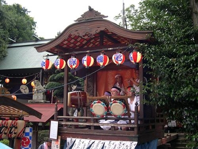 「高倉囃子保存会」と書かれた提灯の付いた山車で太鼓をたたく人の写真
