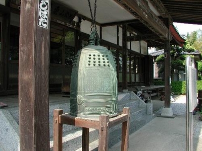 お寺の前の台に置かれた青銅の梵鐘の写真